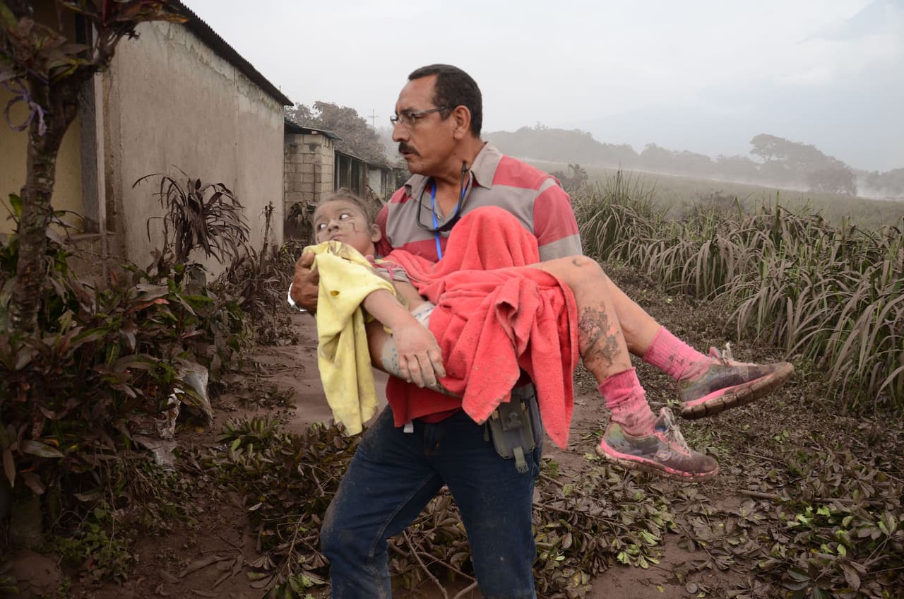 A child rescued from the disaster zone is carried to safety.