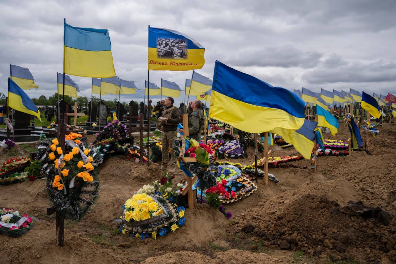 Soldados beben un trago para honrar la memoria de dos soldados fallecidos en el cementerio de Járkov, el 22 de mayo de 2022.