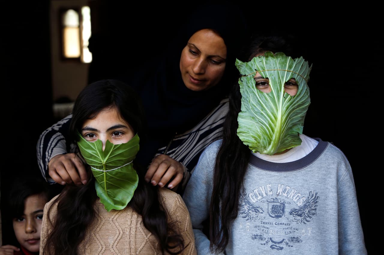 Una madre palestina juega con sus hijos a hacer máscaras protectoras con hojas de repollo, en la Franja de Gaza. 6 de abril.