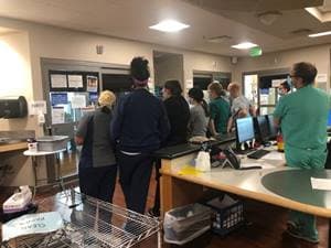 Personal médico del hospital McKay-Dee en Ogden, Utah, se reunen en el exterior de la habitación de un paciente intubado por covid-19 para verlo interpretar el violín.