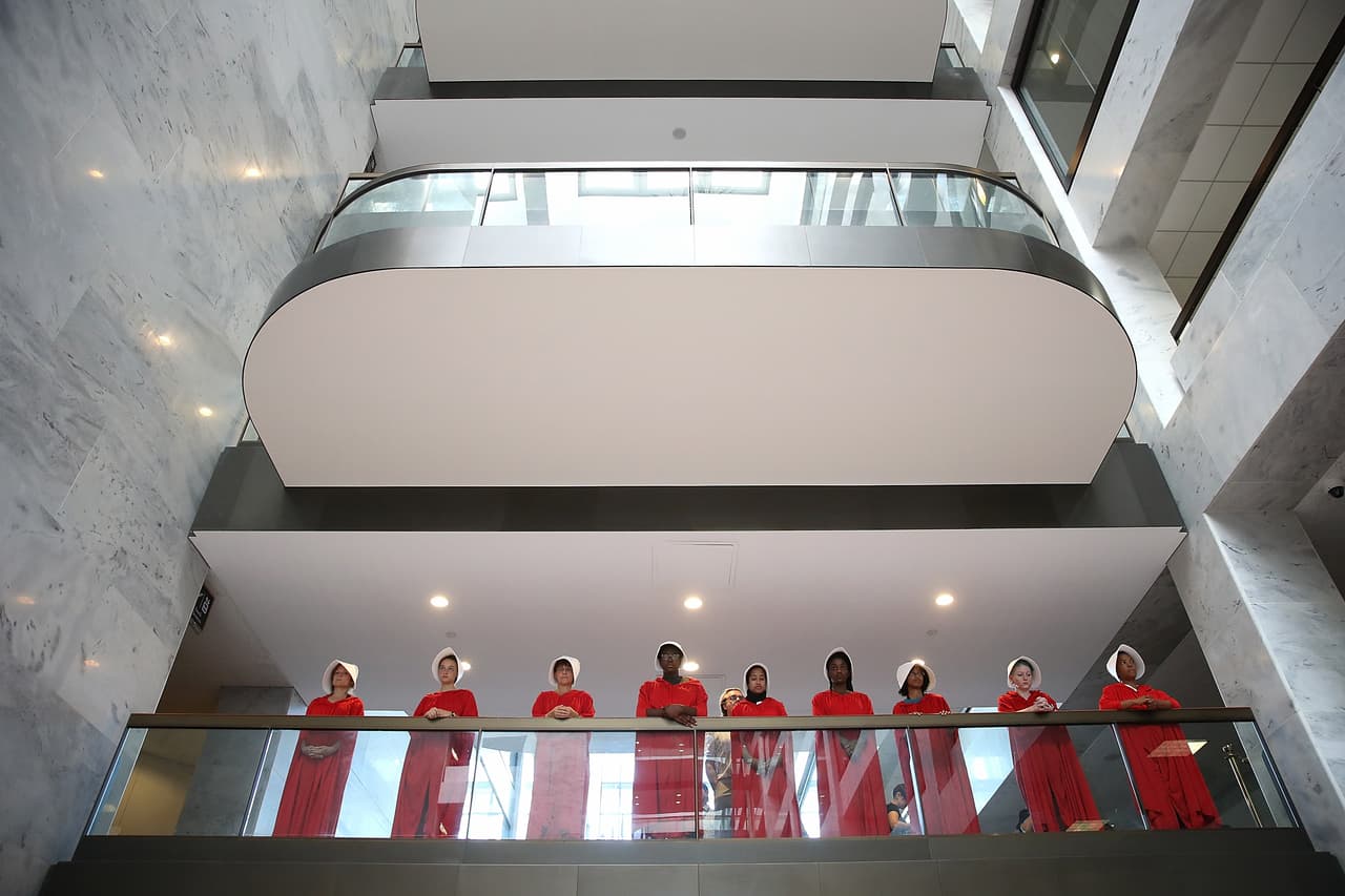 Un grupo de mujeres manifestaron vestidas como los personajes de la serie televisiva 
<i>The Handmaid's Tale</i>, fuera de la sala donde se realizaba la audiencia a Kavanaugh. La serie es la adaptación de la novela de la escritora Margaret Atwood y ha motivado a muchas mujeres activistas a vestirse con capas rojas para protestar contra las amenazas a su salud sexual y su libertad reproductiva.