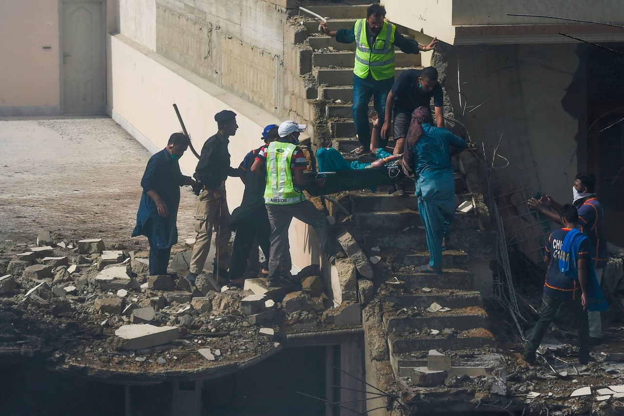 Los trabajadores de emergencia y vecinos remueven a una víctima del accidente. Se desconoce el número total de afectados en este momento pero, al caer, la nave dejó una estela de destrucción en tierra.