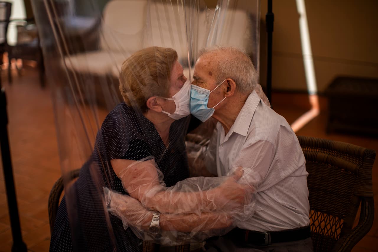 En el asilo de ancianos Ballesol Fabra i Puig de Barcelona se comenzaron a recibir visitas tras más de 100 días de un estricto confinamiento, aunque sin perder el objetivo primordial de salvaguardar la salud de residentes y familiares. 
<br>
<br>Usando máscaras de protección, Agustina Cañamero, de 81 años, y Pascual Pérez, de 84, se besan a través de una pared de plástico para eviatar la propagación del coronavirus. La pareja rompió en llanto al poder darse un abrazo. Es la primera vez que se distancian tanto tiempo en 59 años de matrimonio.
