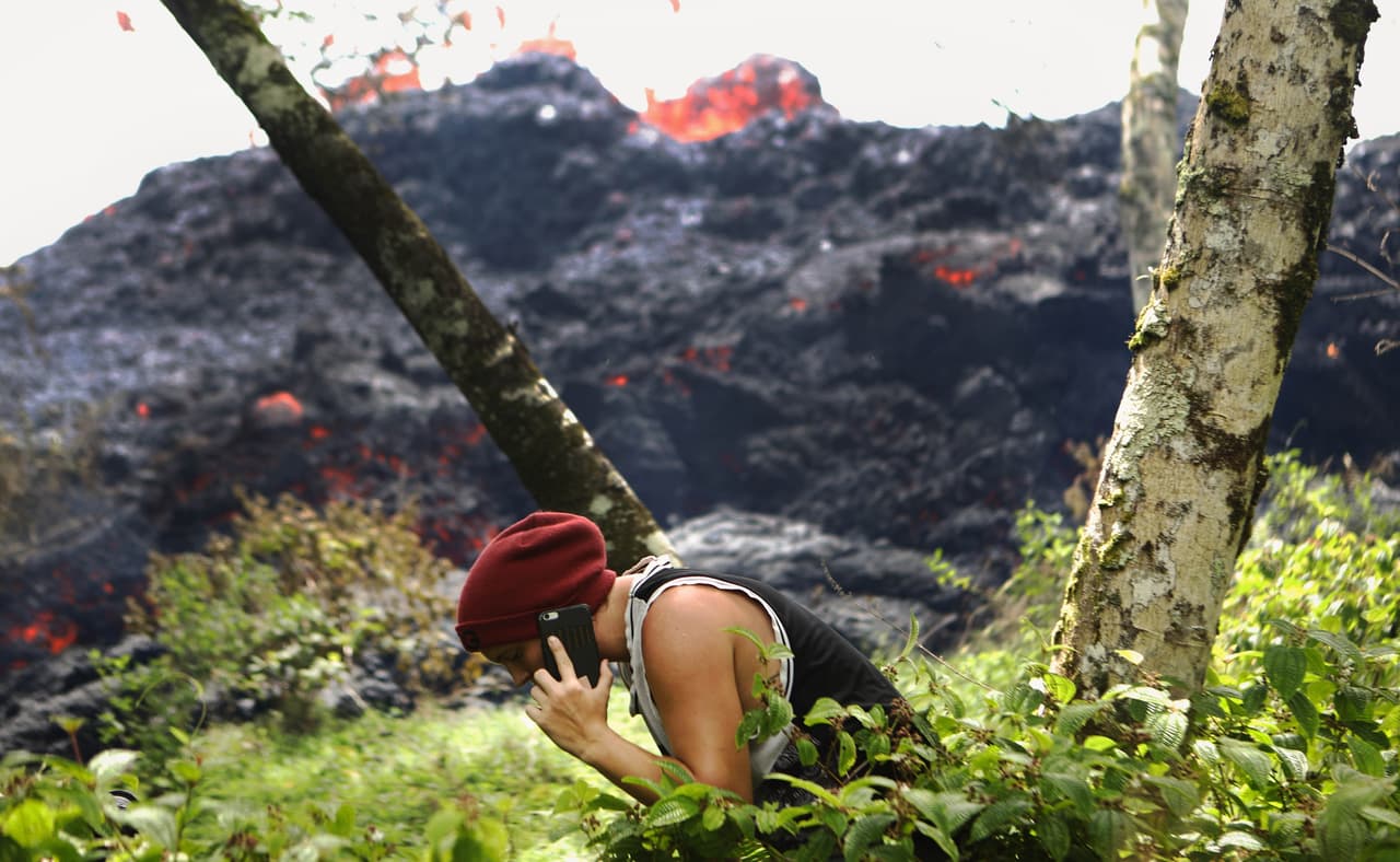 Una espectadora se acerca a un flujo de lava, desde donde también conversó por teléfono. La zona que ha sufrido la mayor parte de la erupción se encuentra a unas 24 millas al este de la caldera principal del volcán.