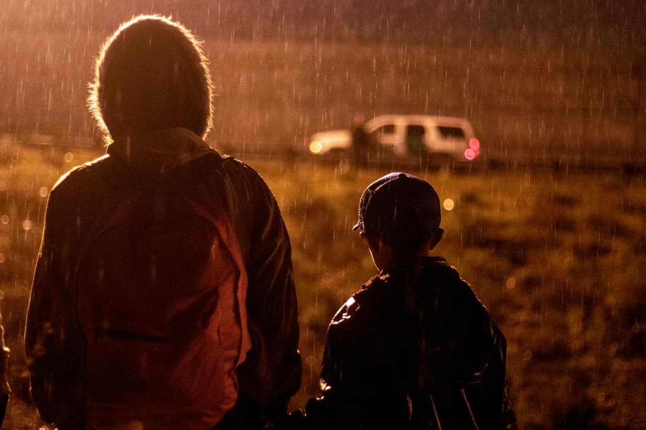 Un grupo de migrantes esperando bajo la lluvia ante la mirada de un vehículo de la Patrulla Fronteriza. Había una veintena de unidades de la fuerza de seguridad y elementos antimotines listos para entrar en acción.