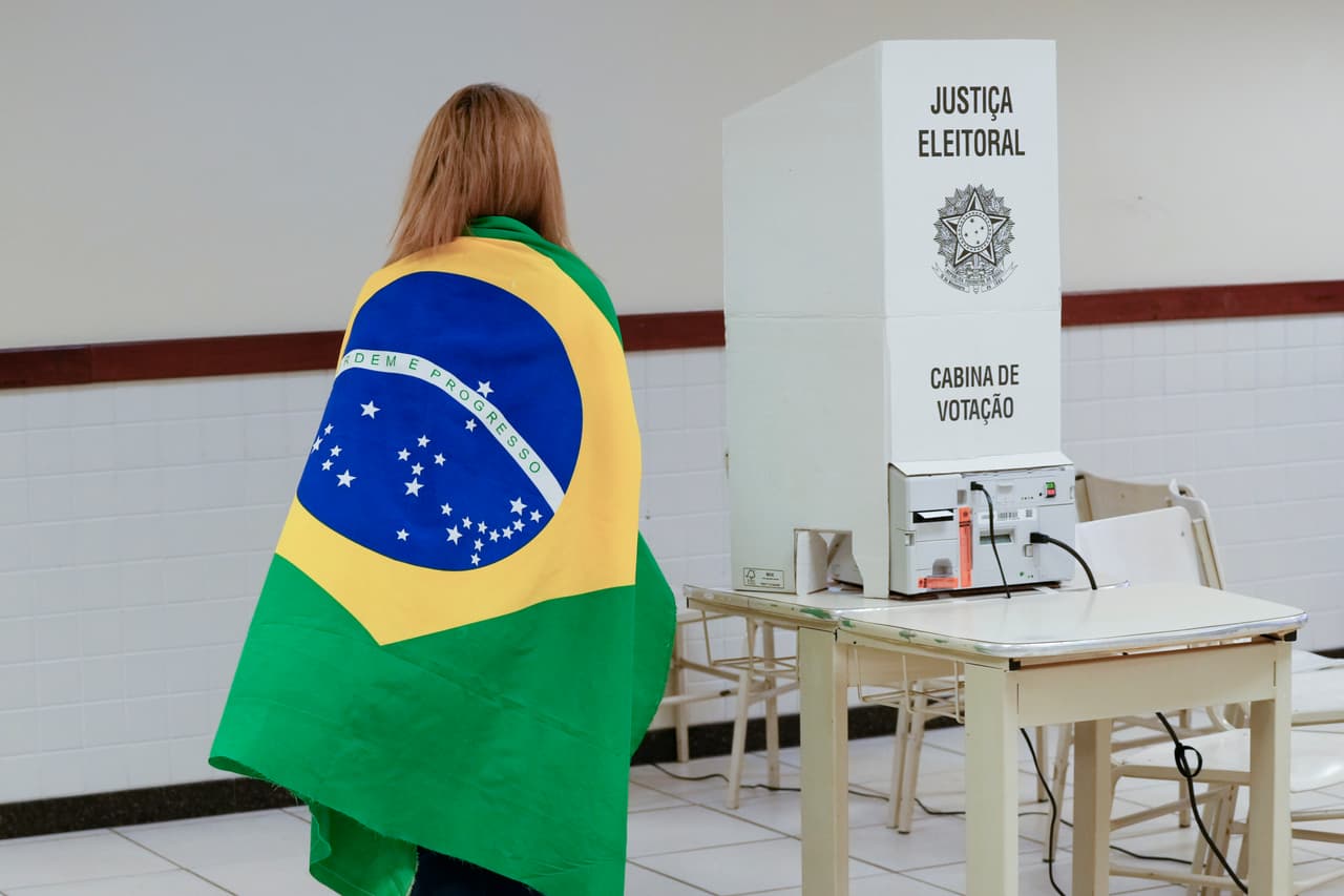 El líder del Partido de los Trabajadores (PT), que ya gobernó entre 2003 y 2010, volverá a ocupar la presidencia de un Brasil extremadamente dividido a partir del 1 de enero de 2023 y por los 4 años siguientes. En la imagen, una votante acude a las urnas con la bandera de Brasil.