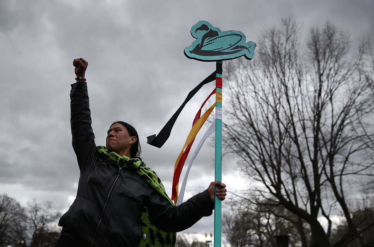 Un activista sostiene un letrero con un maiz ilustrado en la protesta del 10 de Marzo de 12017.