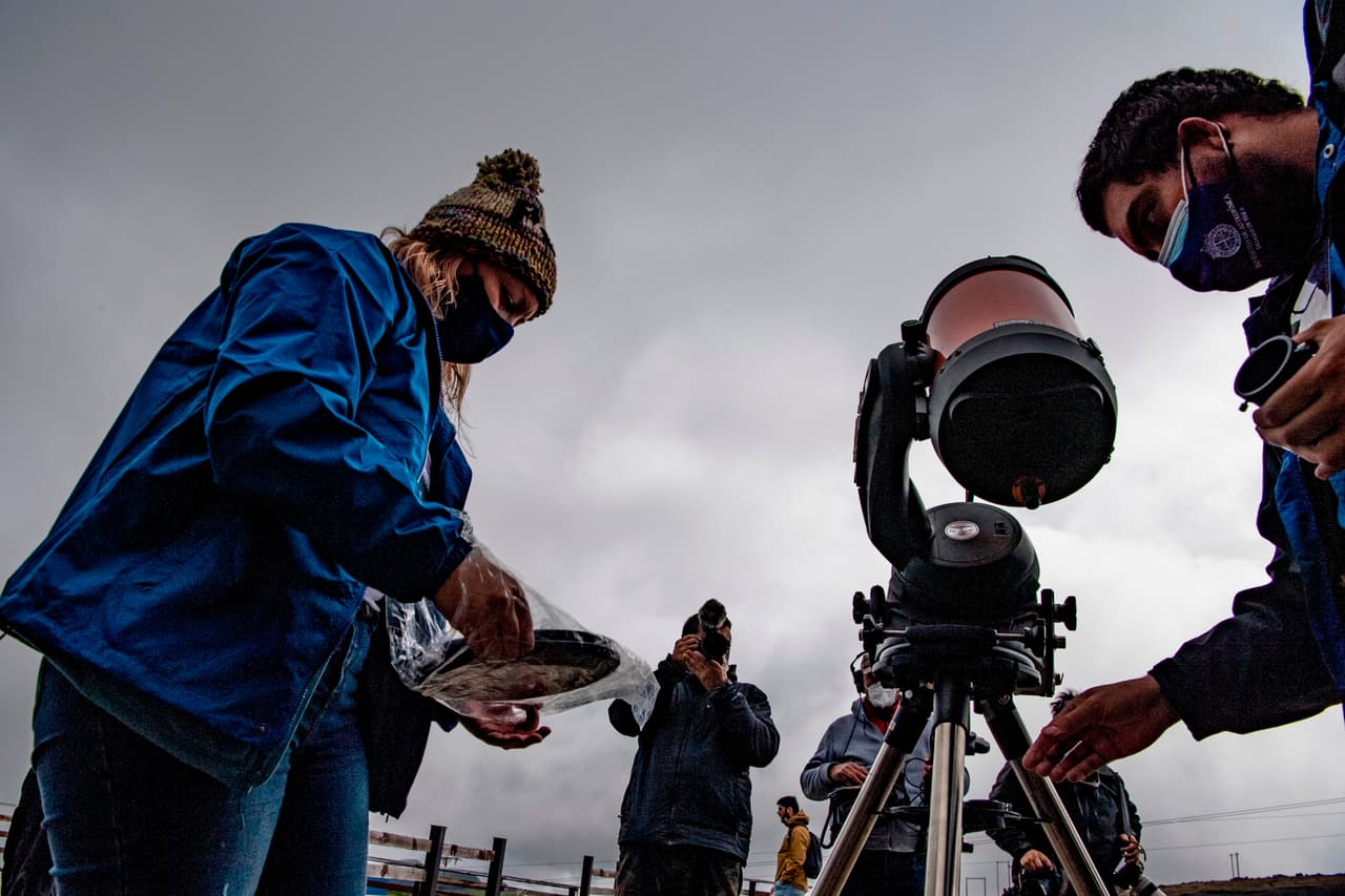 Simon Angel (derecha) y Daniela Fernandez (izquierda), astrónomos de la Universidad Católica de Chile, preparan un telescopio con la finalidad de obervar el eclipse solar, que en la cosmovisión indígena representa "la muerte temporal del Sol". 
<br>
<br>El fenómeno se pudo observar desde cualquier altura, aunque especialmente en varios puntos emblemáticos como el Cerro San Cristóbal, una pequeña montaña que se encuentra en una zona céntrica de la capital, y el Cerro Calán, más al oriente, donde opera un observatorio astronómico.