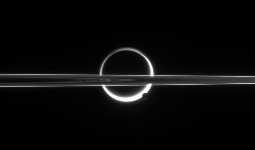 Los anillos de Saturno pasan por delante del aura de Titán, quebrado por la pequeña luna Encelado.