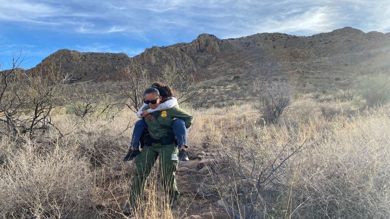 Una agente ayuda a la hija de una mujer que fue encontrada cerca de Amado. Los agentes de la estación Nogales respondieron al llamado de una migrante perdida. La mexicana se encontraba en una montaña, pudieron bajarla y se le brindó primeros auxilios.
