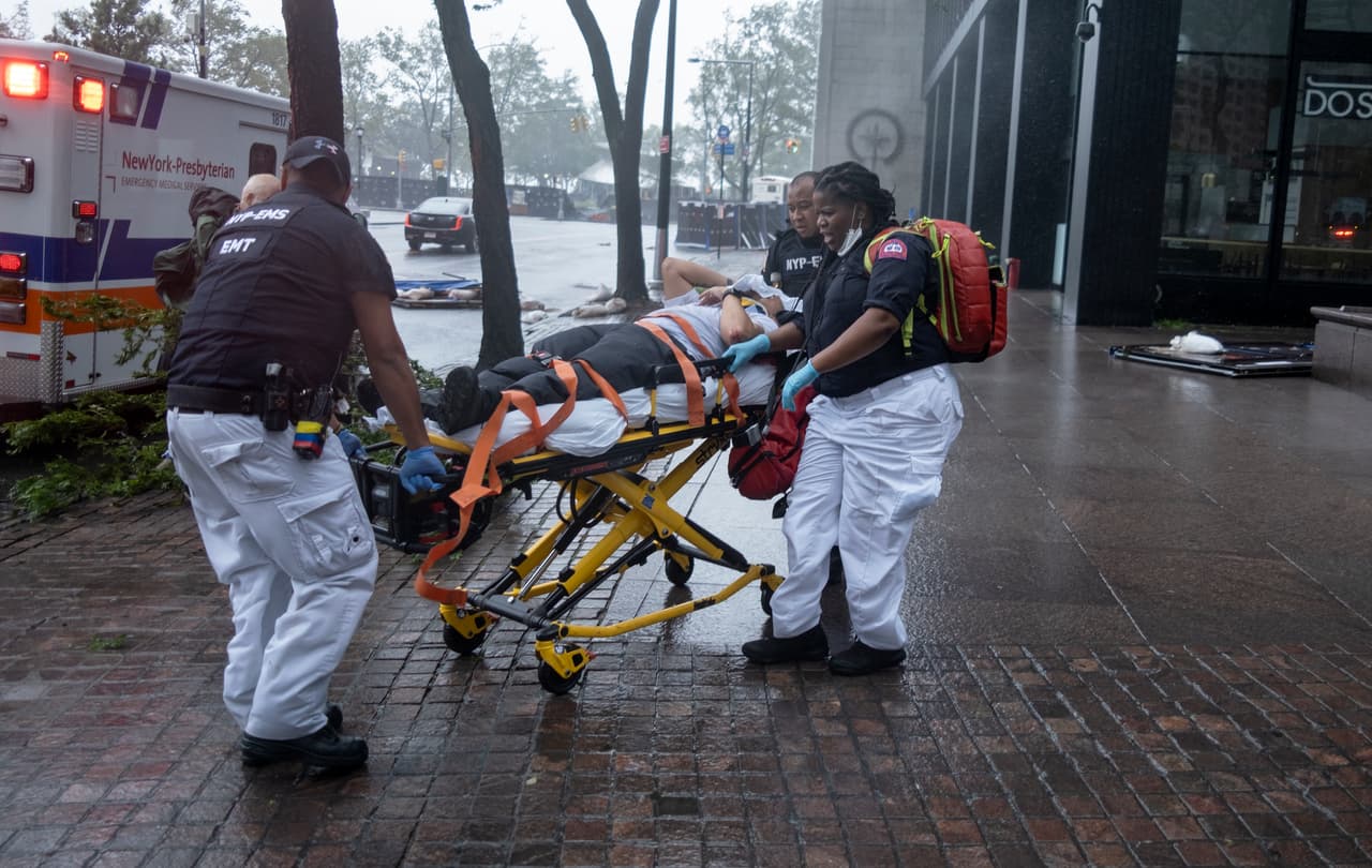 La empresa eléctrica Con Edison dijo que unos 110,000 clientes han sufrido cortes en su suministro dentro de la ciudad, un número de cortes 
<b>que solo fue superado por los vividos durante el huracán “Sandy” (2012) y la tormenta tropical “Irene” (2011)</b>, 
<a href="https://www.ny1.com/nyc/all-boroughs/weather/2020/08/04/isaias-new-york-city-august-4" target="_blank">según informó el canal local NY1. </a>
<br>
<br>En la imagen, una persona que resultó herida mientras intentaba asegurar barreras es transportada para una revisión médica.