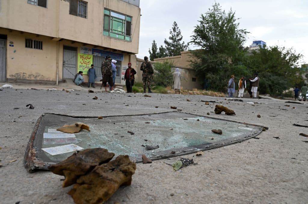 El lunes amaneció con cohetes volando sobre Kabul, en la imagen se pueden observar los restos de un automóvil alcanzado por uno de ellos y cómo militantes talibanes vigilan el lugar.