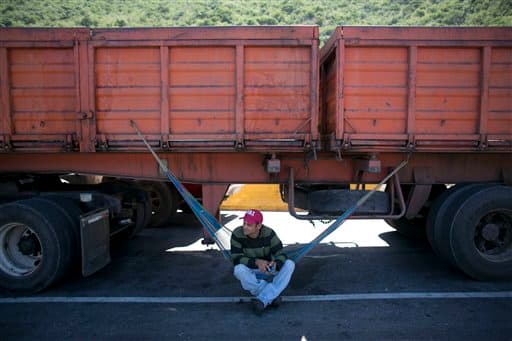 Un camionero descansa en una hamaca bajo su vehículo mientras espera para entrar al puerto en Puerto Cabello en noviembre. Los conductores tienen que esperar días para recoger la carga. Las demoras en la entrada al muelle son un castigo a los propietarios de las empresas de transporte que se niegan a pagar sobornos a los oficiales del ejército, según el presidente de la asociación de camioneros de Puerto Cabello, Jose Petit.