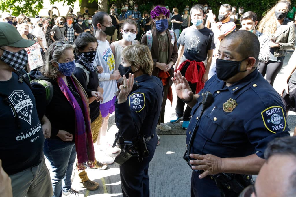 Deanna Nollette y Arian Díaz, jefes asistentes de la policía de Seattle, intentaron entrar este jueves a la sede de la policía que permanece cerrada en la CHAZ, pero fueron recibidos por una cadena de manifestantes que les cerraba el paso.