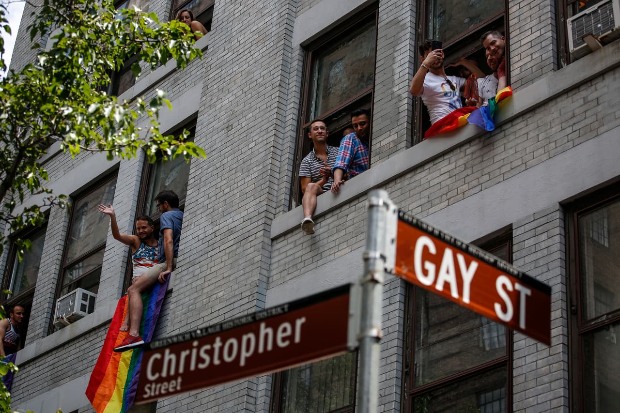 Espectadores aplauden a los participantes el desfile dedde las ventanas de sus apartamentos a lo largo de la avenida Christopher.