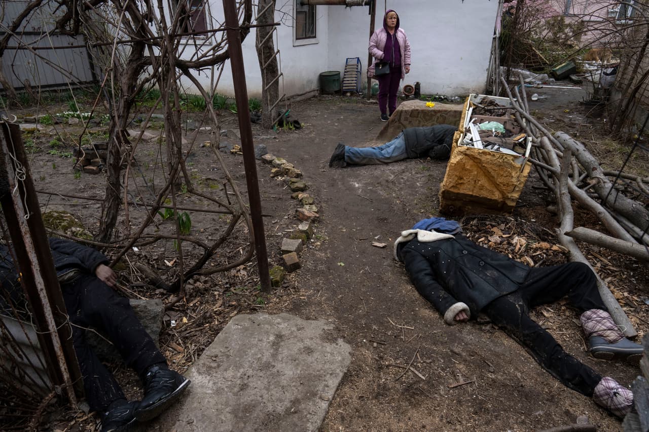 El sombrío trabajo para Minchenko y un pequeño grupo de otros comenzó bajo la ocupación cuando los cuerpos esparcidos por las calles o arrojados apresuradamente en los patios. En la imagen, una mujer junto a tres cadáveres en el patio 
<a href="https://www.univision.com/noticias/mundo/horrores-bucha-retirada-ejercito-ruso" target="_blank">de una casa en Bucha</a>, a las afueras de Kiev.