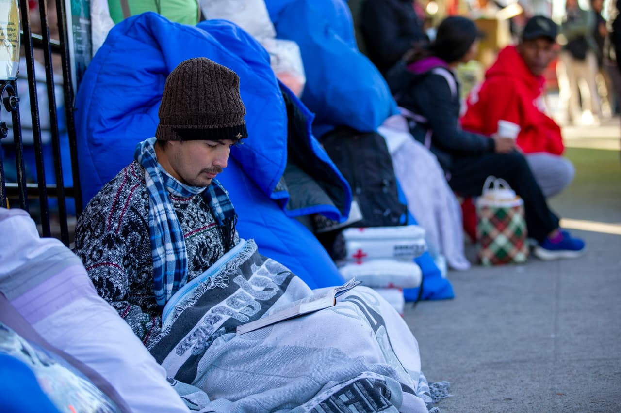 Un inmigrante lee la biblia mientras se encuentra en un refugio afuera de la iglesia del Sagrado Corazón en El Paso, Texas, este 8 de enero de 2023, el mismo día en que el presidente Joe Biden visitó la ciudad en medio de críticas por su gestión de la crisis de inmigración en la frontera sur.