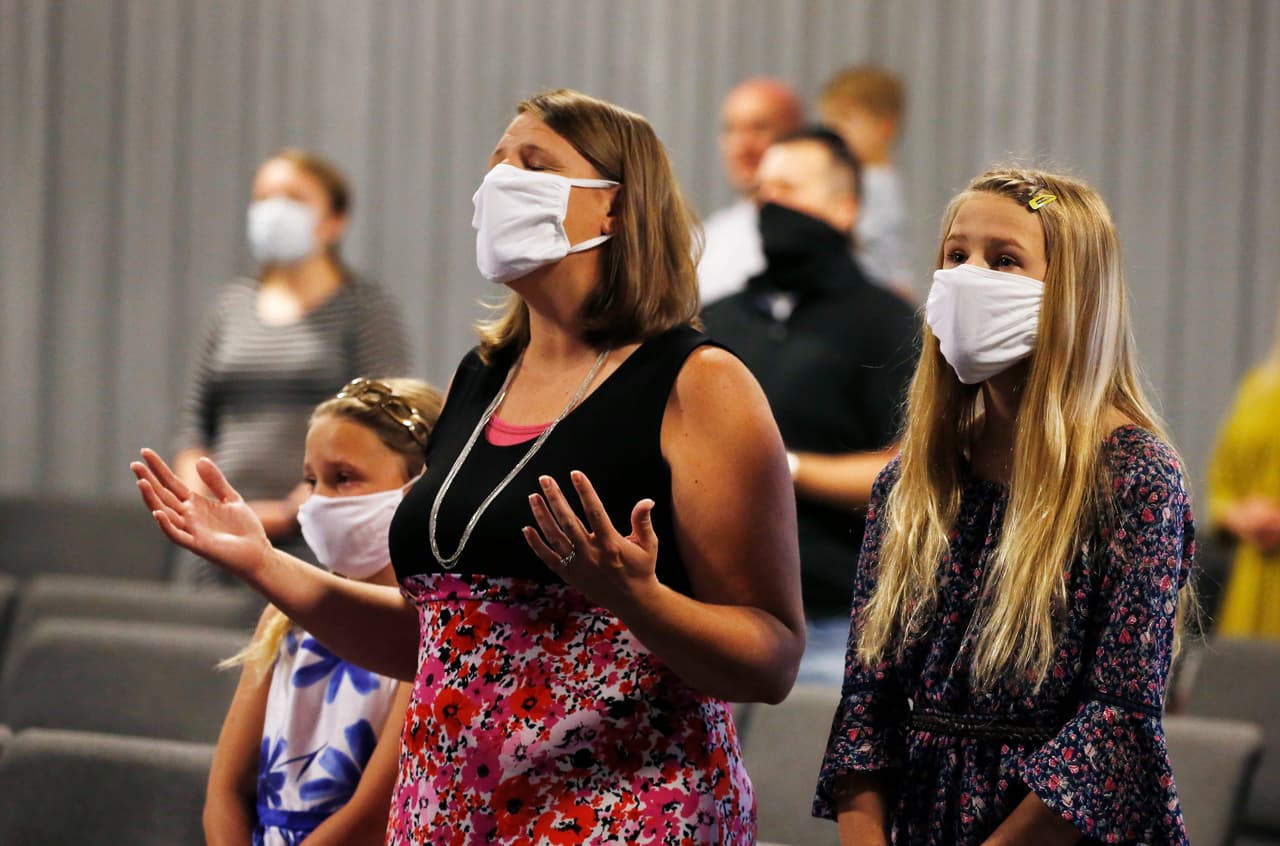 Los feligreses cantan durante un servicio en la Iglesia de la Biblia de la Gracia el domingo 24 de mayo de 2020, en Tempe, Arizona. Practicaron el distanciamiento social, la mayoría usando cubiertas para la cara, ya que la iglesia celebró su primer servicio en persona desde marzo debido al coronavirus.