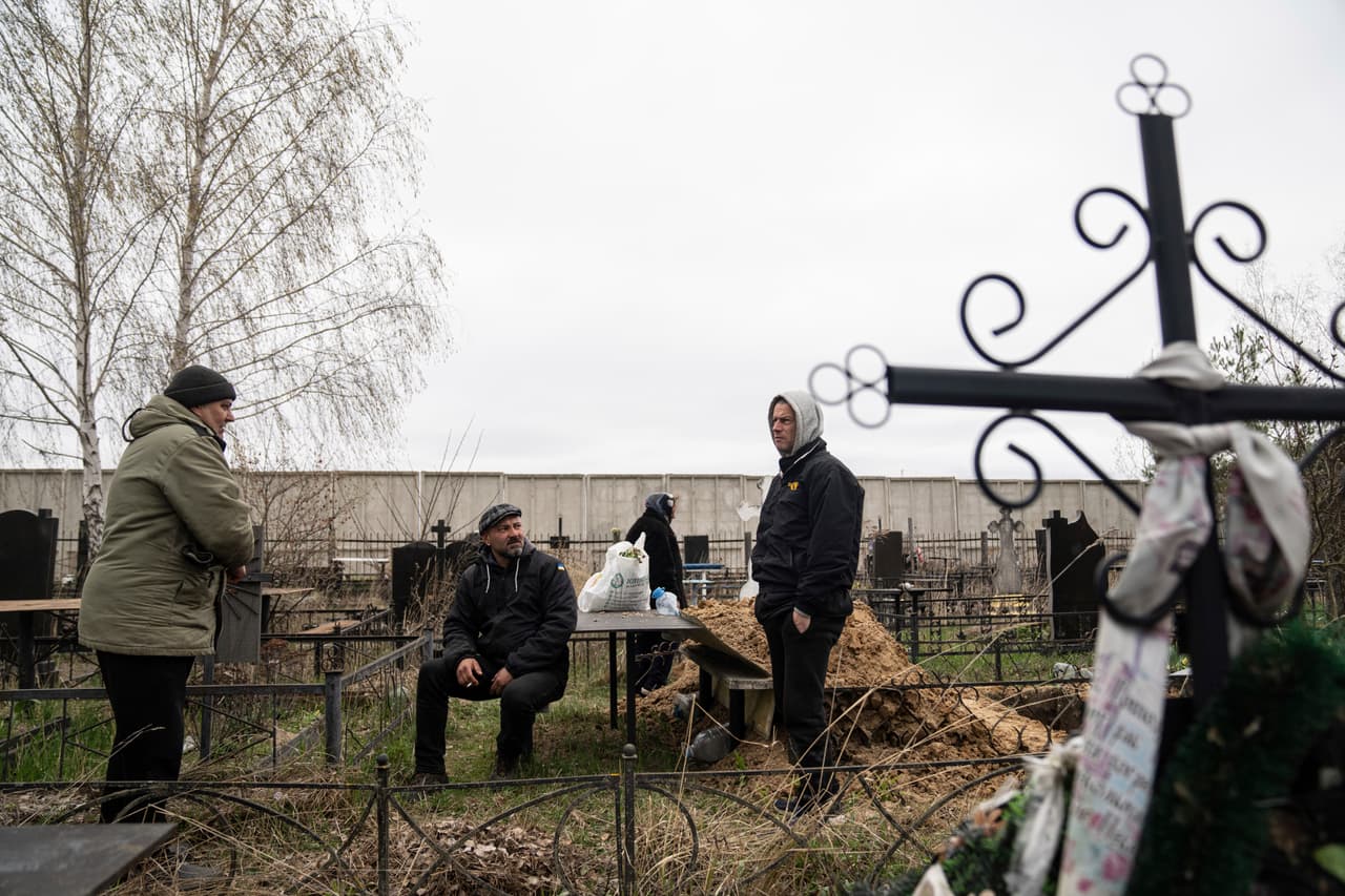 Vlad Minchenko, segundo por la izquierda, fuma un cigarro en el cementerio durante un descanso de su trabajo. Ahí ayuda a cavar las tumbas y ofrece consuelo a familiares, aún conmocionados por lo ocurrido.