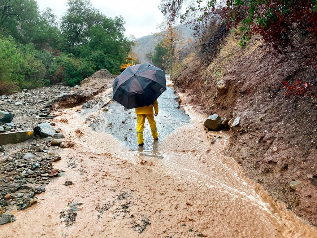 Un residente local examina los daños de una carretera arrasada en el Cañón Silverado, California, el martes 14 de diciembre de 2021. En el condado de Orange, al sur de Los Ángeles, unas 800 casas del cañón estaban bajo órdenes de evacuación el martes después de que se emitiera una advertencia de inundación repentina y se informara de deslizamientos de tierra en la zona, calcinada por el 
<a href="https://www.univision.com/local/los-angeles-kmex/incendio-bond-destruye-mas-de-3-600-acres-en-california">incendio forestal de Bond en 2020</a>.