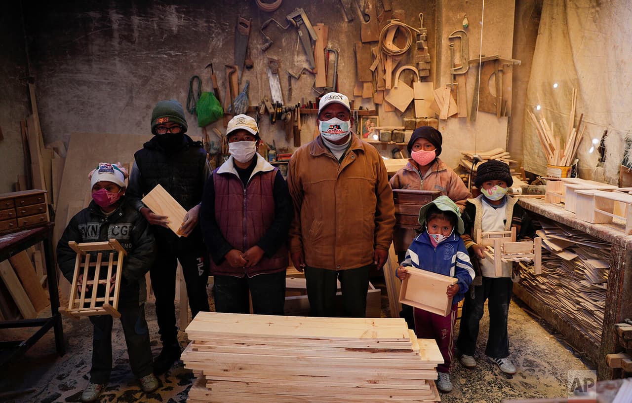 Al igual que en México, la situación en Bolivia tiene a los pequeños de lleno en laborales lejos de las escuelas cerradas. Con máscaras protectoras para frenar la propagación del virus, la familia Delgado posa para una foto en su taller de carpintería en El Alto, 
<a href="https://www.univision.com/temas/bolivia">Bolivia</a>. 
<b>Después de que el gobierno canceló el año escolar, los cinco niños de entre 6 años y 14 trabajan allí con sus padres. </b>