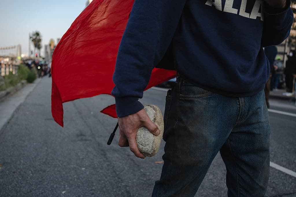 Horas más tarde, manifestantes, como el captado en la foto, agredieron a pedradas a los oficiales que intentaban desalojarlos de la 
<b>autopista 101</b>, a donde se movilizó la protesta, luego de que agentes federales, respaldados por tropas de la Guardia Nacional, los desalojaran con 
<b>gases lacrimógenos</b> de los predios del Centro de Detención Metropolitano de ICE, en Los Ángeles.
