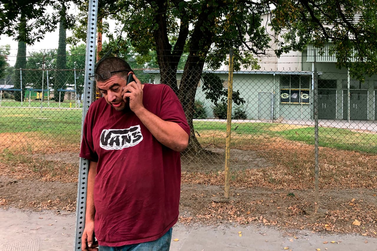 Douglas Johnsrude habla por teléfono en un centro de evacuación de emergencia en Gridley, California. Johnsrude evacuó su casa en Feather Falls 
<b>y cree que perdió su casa en el incendio, pero no está seguro.</b> La situación no es nueva para él, ya que había perdido su antiguo hogar en el Ponderosa Fire en 2017. 
<br>