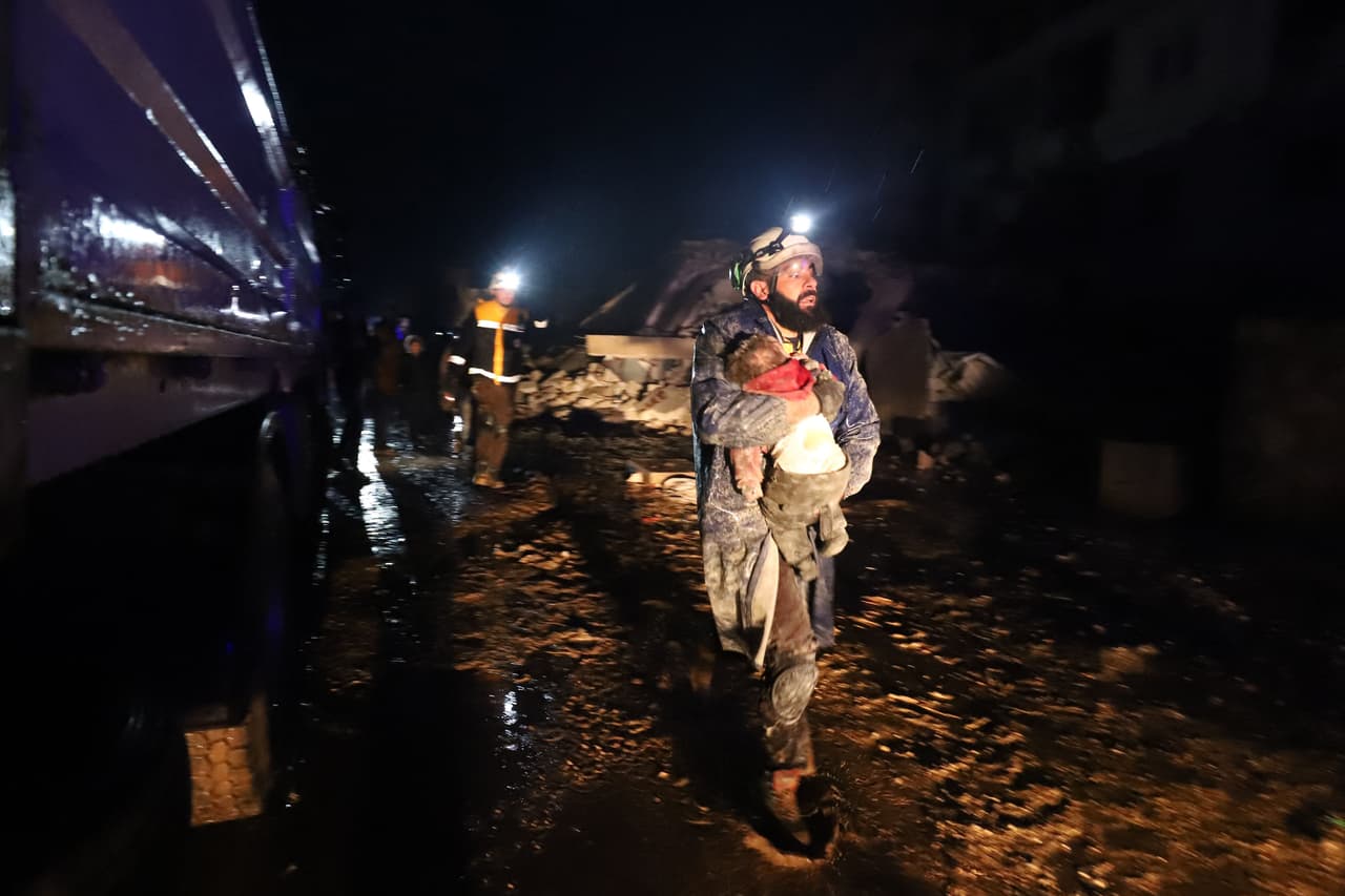 Un voluntario de los Cacos Blancos en Siria lleva en sus brazos a un bebé que lograron rescatar de entre los escombros de un edificio en la ciudad de Zardana.