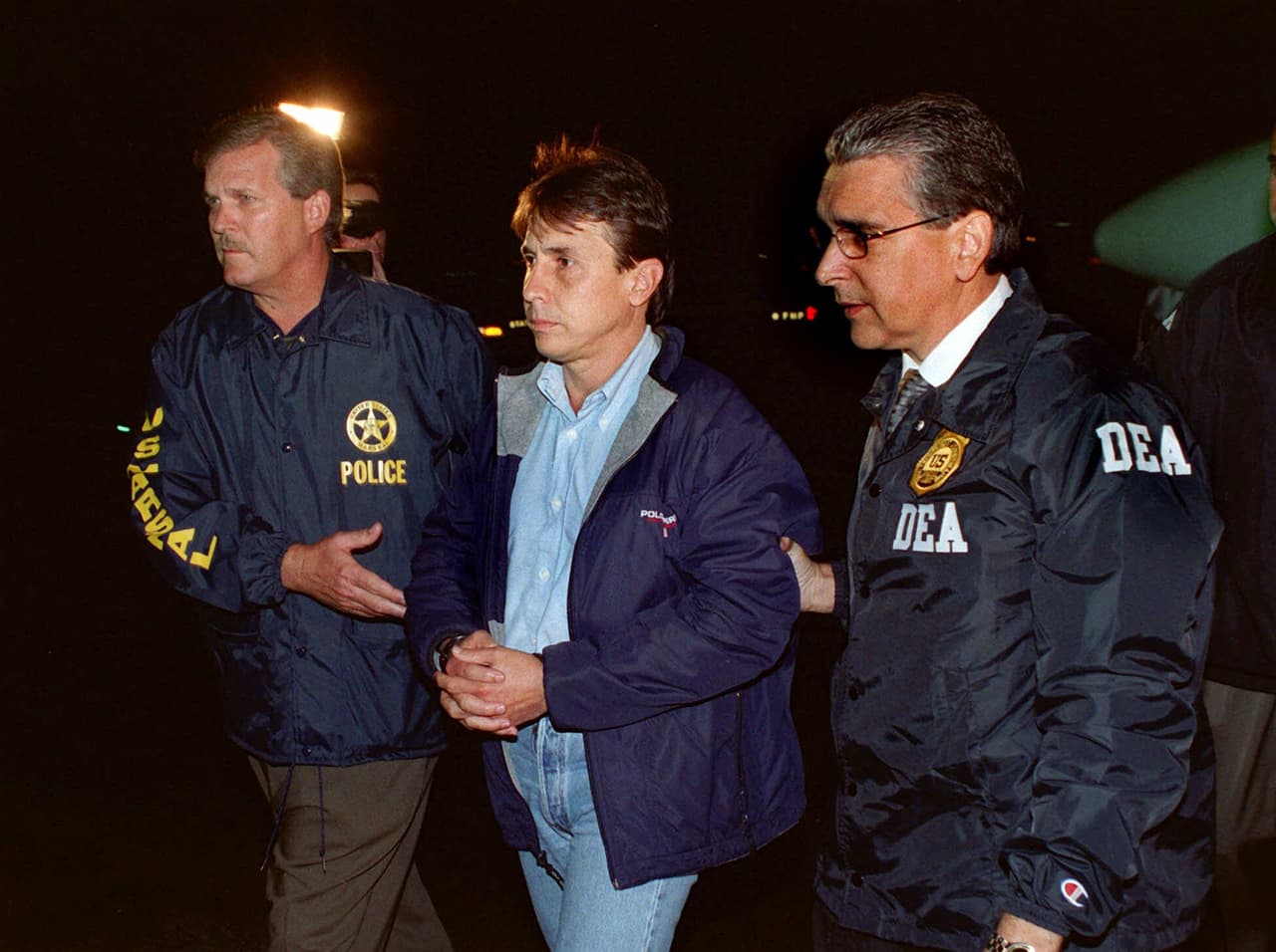 Los agentes de la Administración de Control de Drogas (DEA) y alguaciles de los Estados Unidos acompañan a Fabio Ochoa, a un vehículo en espera en el Aeropuerto Internacional de Miami, 8 de septiembre de 2001, después de su extradición de Colombia.