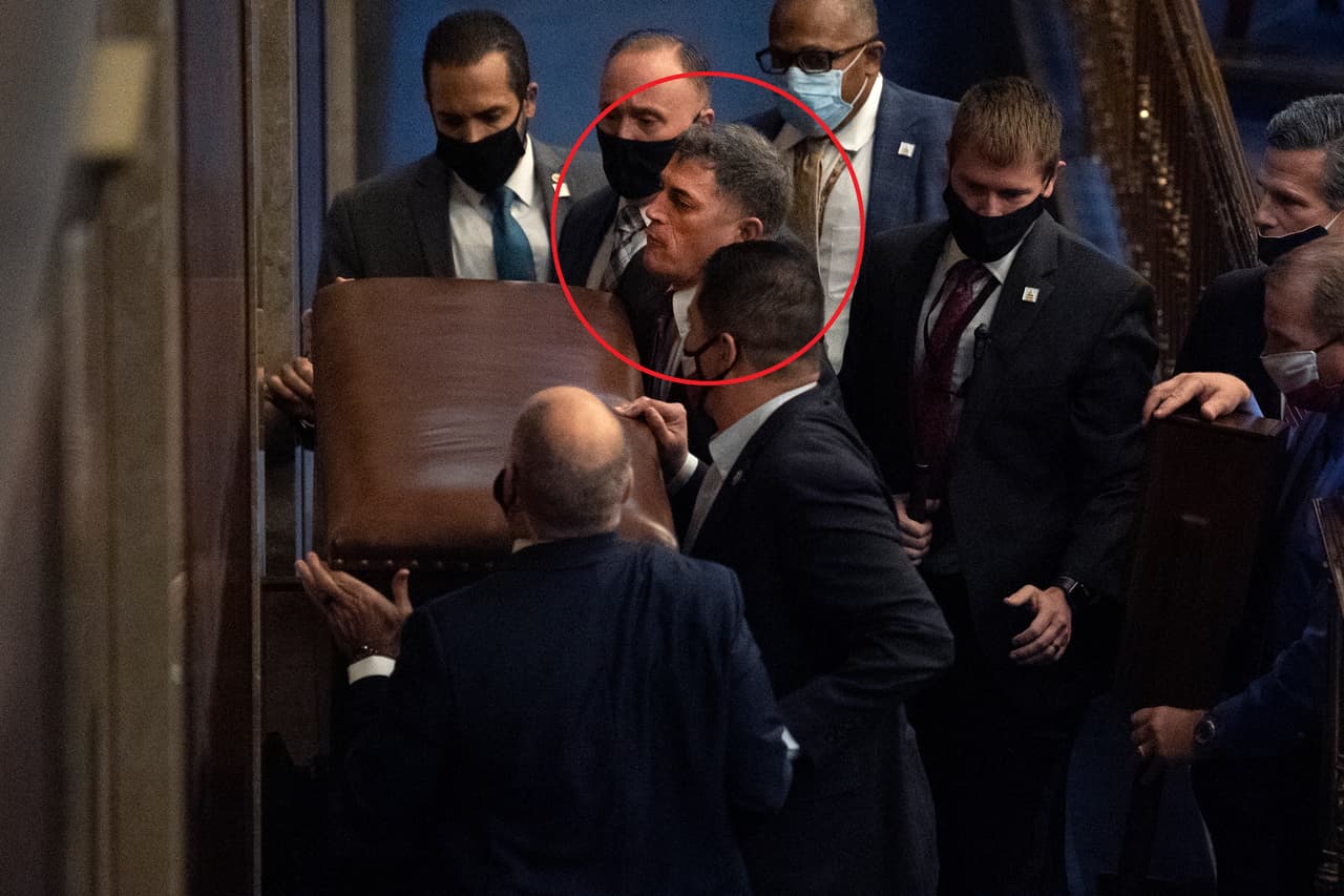 El representante Andrew Clyde, dentro del círculo, bloquea junto a un grupo de guardias de seguridad la puerta de la Cámara. Intentaban cerrar el paso a una multitud de seguidores de Trump que interrumpió la sesión conjunta del Congreso el 6 de enero.