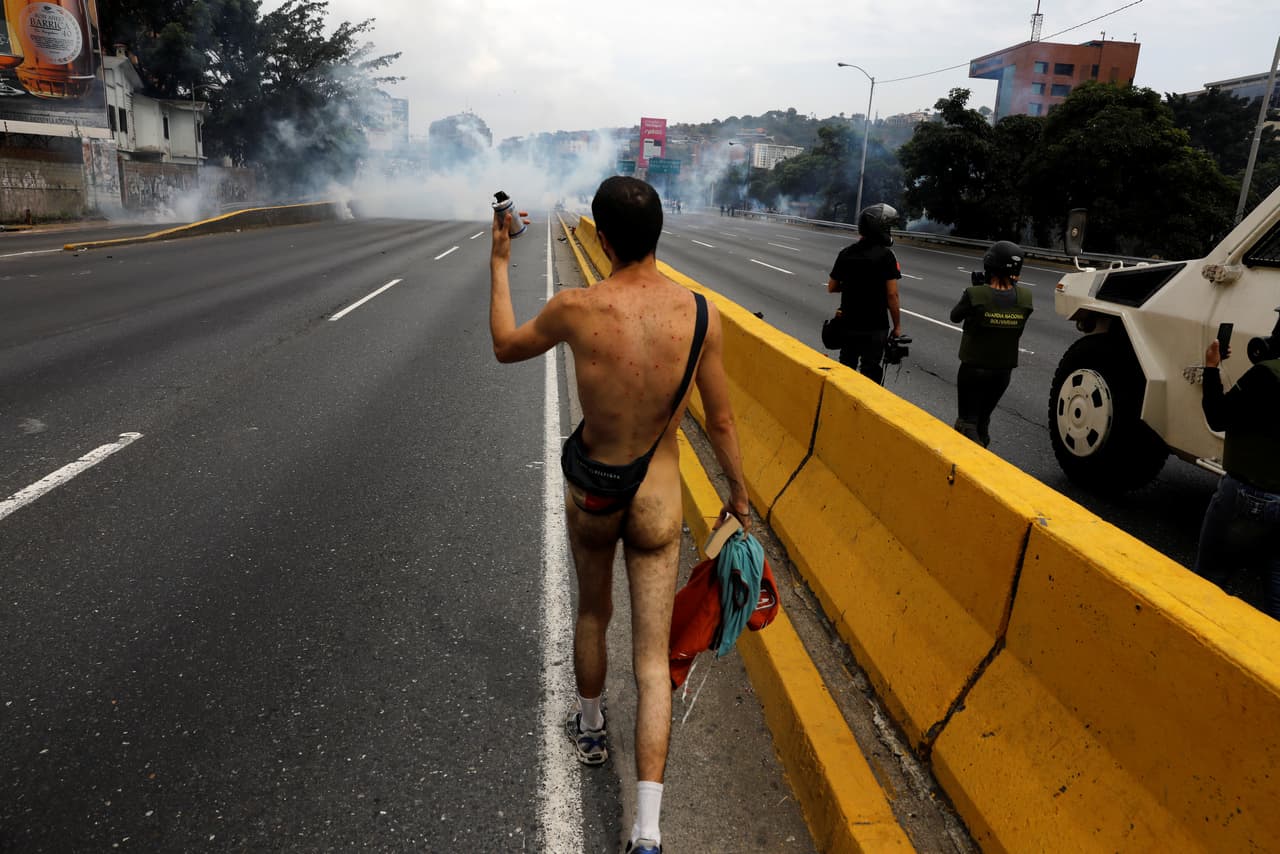 Mientras la policía le lanzaba bombas, él, desnudo, continuaba caminando. (Carlos García Rawlins/Reuters)