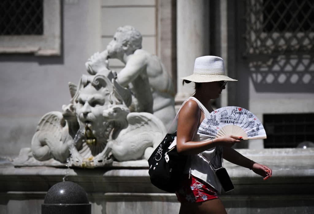 Una mujer con un abanico camina en la Piazza Navona en Roma el 17 de julio de 2023, durante una ola de calor en Italia.