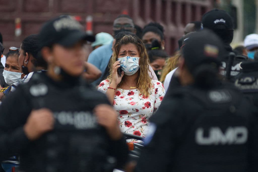 Una mujer habla por teléfono entre lágrimas y espera tener noticias de su familiar, que está dentro de la prisión.
