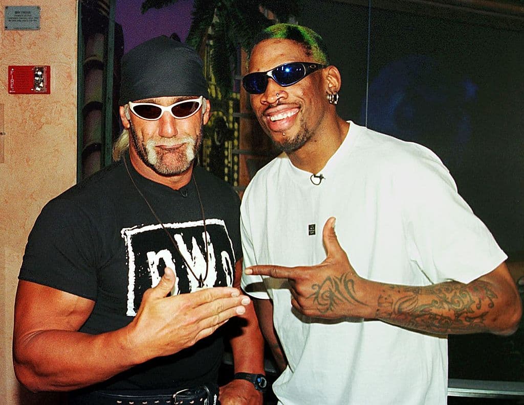 <b>Un personaje más grande que el ring. </b>Su estilo teatral, su físico imponente y su carisma lo volvieron ícono cultural. El gesto de romperse la camiseta antes de cada combate se volvió una marca registrada. Hogan encarnó el arquetipo del héroe musculoso e invencible, lo que le ganó millones de fanáticos, conocidos como "Hulkamaniacs". En la imagen aparece en compañía del basquetbolista Dennis Rodman.