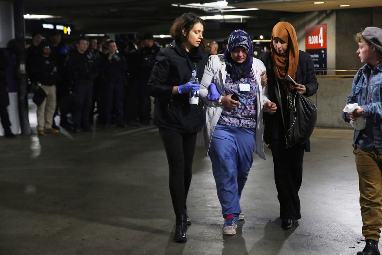 Saffiya Hrahsheh, en el centro, es ayudada tras recibir gas pimienta utilizado por la policía para dispersar a aproximadamente 3,000 manifestantes que se reunieron en el Seattle-Tacoma International Airport.