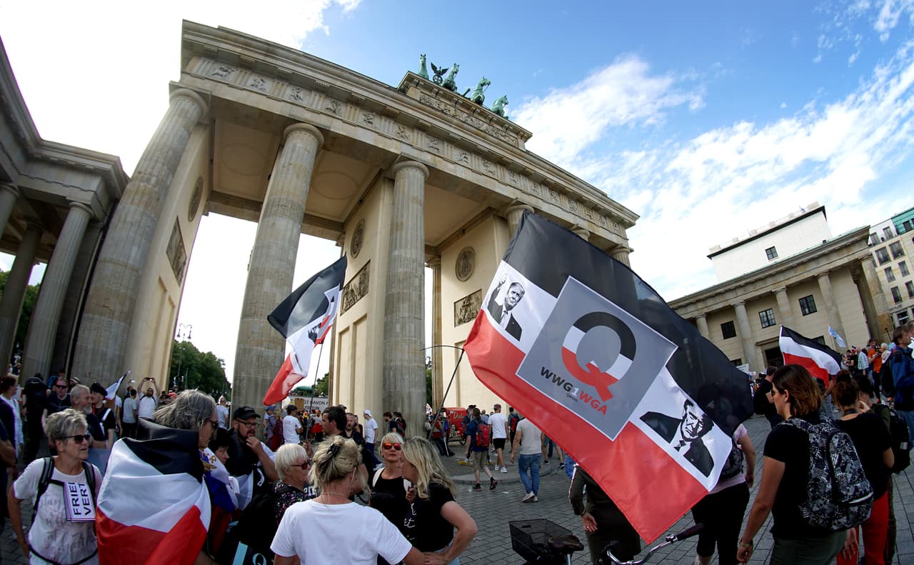 Decenas de miles de personas se reunieron el sábado en la famosa Puerta de Brandenburgo de Berlín, en Alemania, y luego marcharon por el bulevar Unter den Linden para rechazar las restricciones que ha impuesto el gobierno de Alemania, que ha experimentado un reciente repunte de covid-19. En la imagen, se observan banderas con el rostro de Donald Trump.
