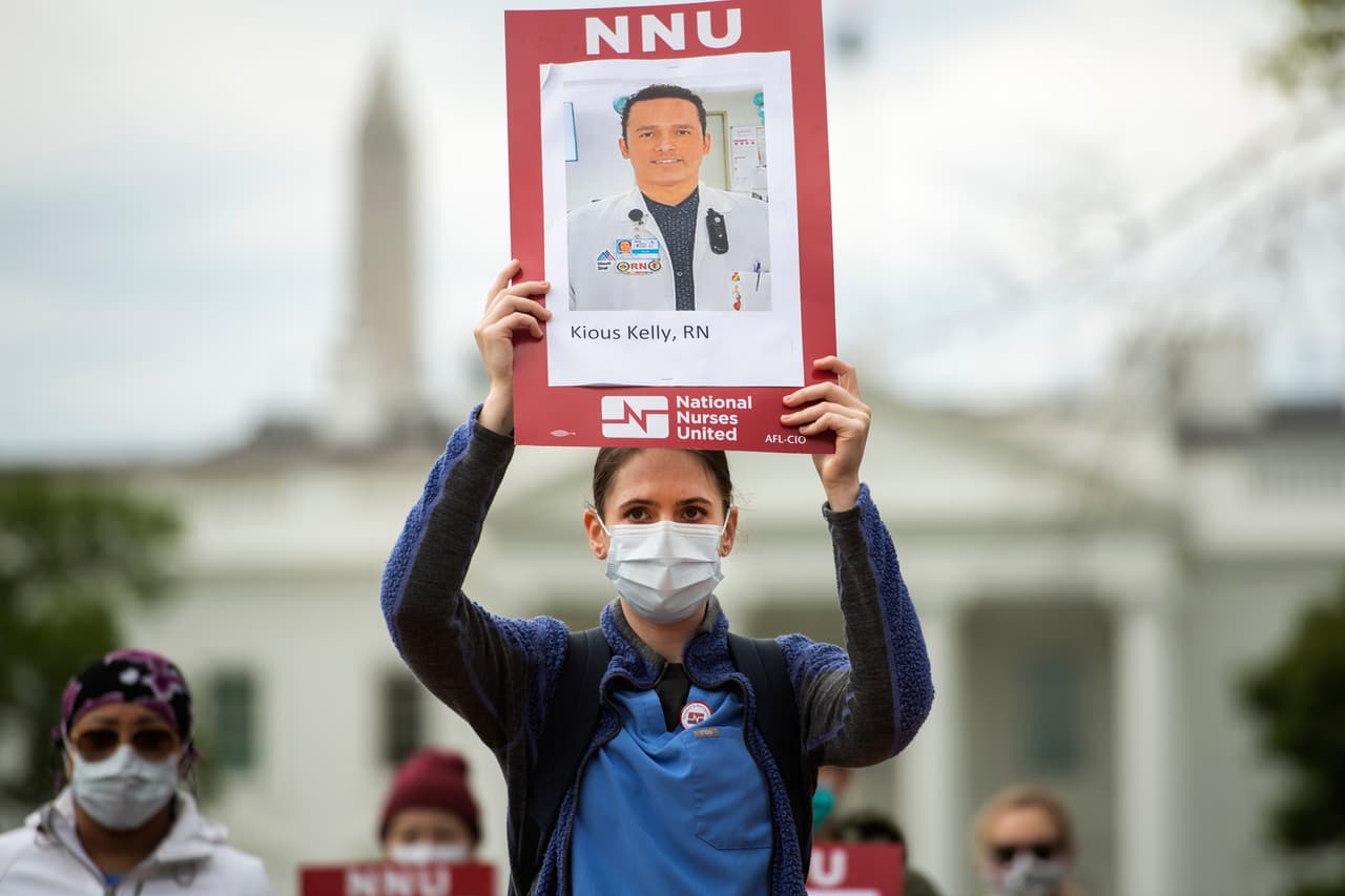 <b>Estados Unidos: 1,077 trabajadores de la salud muertos por covid-19. </b>Amnistía Internacional revisa y recopila periódicamente estos datos de diversas fuentes, que incluyen páginas conmemorativas, medios oficiales, listas de asociaciones médicas nacionales y obituarios publicados en medios de todo el mundo. En la fotografía un grupo de enfermeras exigiendo más y mejores equipos PPE frente a la Casa Blanca a principios de abril. Llevaron carteles con el rostro de Kious Kelly, uno de los primeros trabajadores de la salud muertos por el covid-19 en el país.
