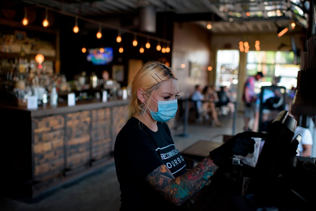 Una empleada utiliza una mascarilla al atender clientes en Houston (Texas). La decisión de usar mascarillas ha llevado incluso a protestas debido a la petición de imponer multas y detenciones a los habitantes que las desobedecieran.