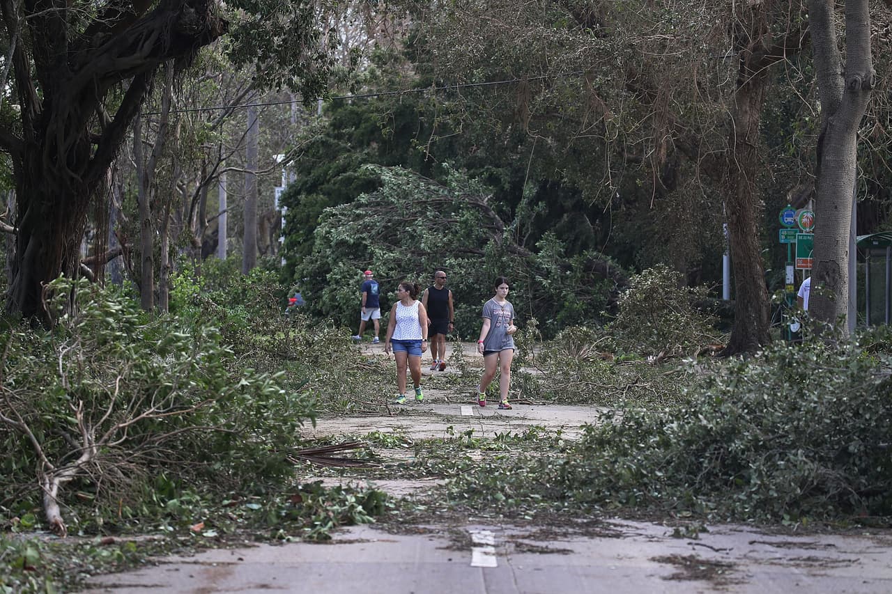 Cientos de árboles cayeron en varias partes de la península de Florida. Muchos de esos árboles cayeron en los cables de tendido eléctrico causando cortes de energía. La imagen es de residentes caminando por una calle en la ciudad de Miami.