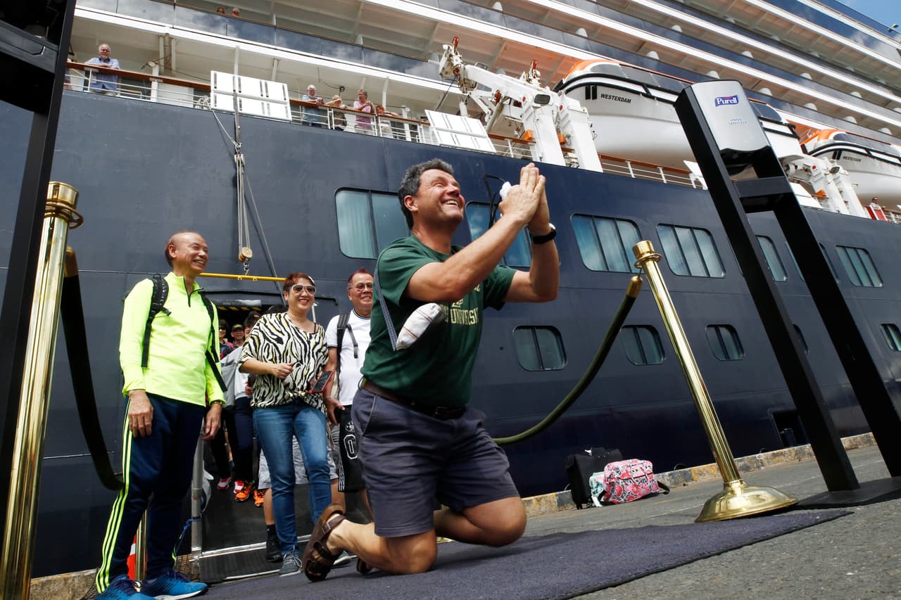 Los pasajeros de un crucero que había sido rechazado en varios puertos de Asia por temor a que pudieran transmitir el nuevo coronavirus comenzaron finalmente a desembarcar el viernes en un puerto de Camboya. En la foto, un viajero de rodillas, agradece a Camboya por dejarlos bajar.