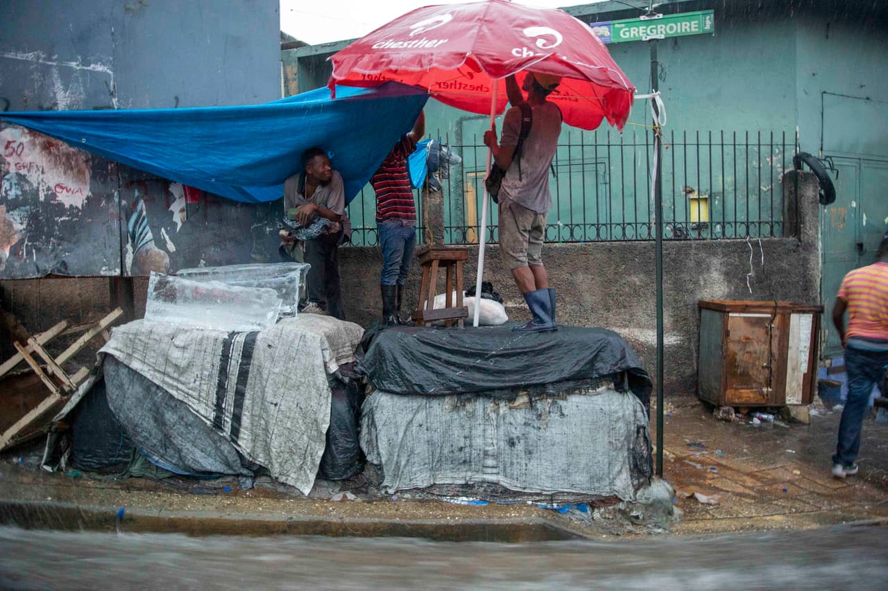 Vendedores ambulantes se protegen de las lluvias en Puerto Príncipe, Haití. 
<br>
<br>Laura provocó la suspensión del servicio eléctrico y de agua en la isla La Española, se espera que en su recorrido hacia Estados Unidos pase por Cuba entre el domingo y el lunes antes de llegar al Golfo de México.