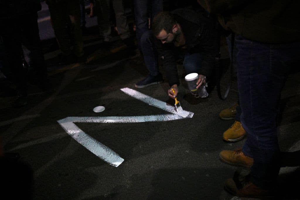 Desde que comenzó la operación, muchos rusos han agregado una "Z" a su nombre en redes sociales, reflejando la letra estampada en el costado de los camiones de transporte militar rusos. 
<b>La "Z" se ha transformado en un símbolo de apoyo a la invasión de Rusia. </b>
<br>
<br>En la imagen, manifestante pinta la letra "Z" en una calle, en referencia a los tanques rusos marcados con la letra, durante una manifestación organizada por sectores de derecha ultranacionalistas en Serbia en apoyo a Rusia, en Belgrado el 4 de marzo de 2022.