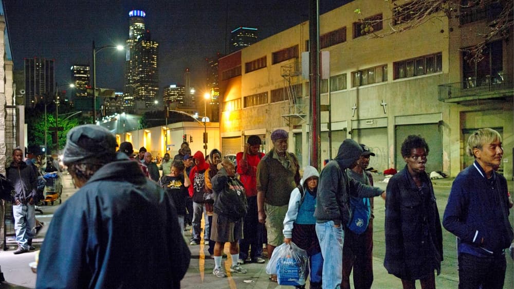 Indigentes hacen fila para recibir comida en uno de los tantos albergues que hay en Skid Row.