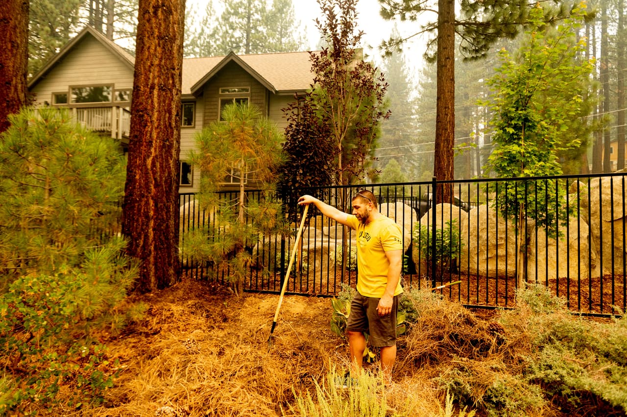 James Campos, residente de South Lake Tahoe, limpia la vegetación acumulada afuera de su casa para intentar que se propaguen las llamas con mayor velocidad.