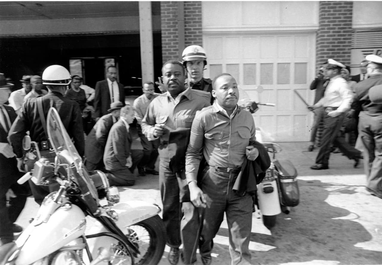 <b>Protestas contra la segregación en Birmingham (Alabama, 1963)</b>
<br>
<br>King y otros líderes organizaron a la población afroestadounidense para manifestar pacíficamente contra la segregación en los comercios y animar a los propietarios a ofrecer empleos a personas de todas las razas. Sentadas en restaurantes y bibliotecas, personas negras de rodillas en las iglesias reservadas a los blancos y marchas de protesta provocaron el arresto de cientos de manifestantes, incluido el propio King (en la fotografía durante un arresto). 
<br>
<br>La ola represiva fue cubierta ampliamente por los medios de comunicación y finalmente las autoridades de la ciudad cedieron y los lugares públicos fueron abiertos a toda la población.