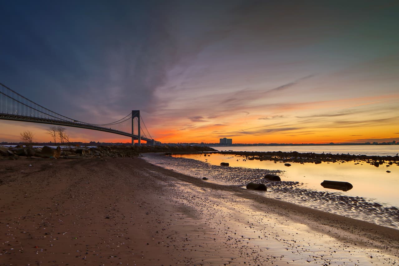 <b><a href="https://www.nycgo.com/boroughs-neighborhoods/staten-island/south-beach-midland-beach">South Beach- Staten Island</a></b>
<br>Father Capodanno Blvd & Sand Ln.
<br>Tel.
<b> </b>· (718) 816-6804
<br>
<a href="https://www.google.com/maps/dir/South+Beach,+Staten+Island,+NY+10305/@40.5904916,-74.1368482,12z/data=!4m9!4m8!1m0!1m5!1m1!1s0x89c24f1840b4ef61:0xf54d3c531ff4193e!2m2!1d-74.0668076!2d40.5903824!3e0">Cómo llegar</a> 
<br>Aquí, puedes relajarte observando una preciosa vista del puente Verazzano, mientras chapoteas en el agua, o tomas un baño de sol en la orilla. Muchos aprovechan el panorama para pedalear en bicicleta, trotar o patinar. 
<br>
<br>De rigor es pasear por Ocean Breeze, 
<b>uno de los muelles más populares de la ciudad. </b>
<br>