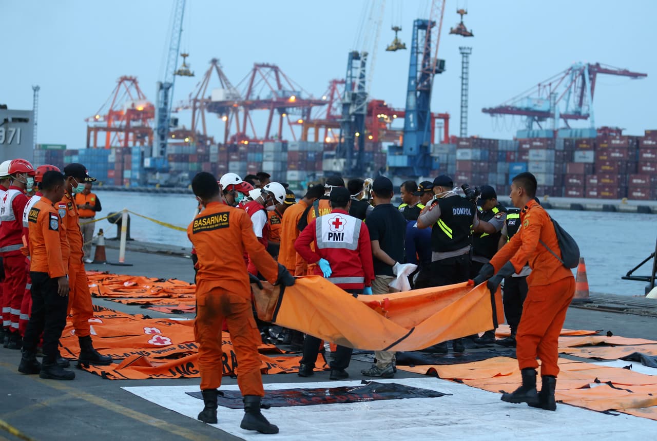 Los funcionarios cargan los cuerpos de las víctimas fallecidas durante el accidente.