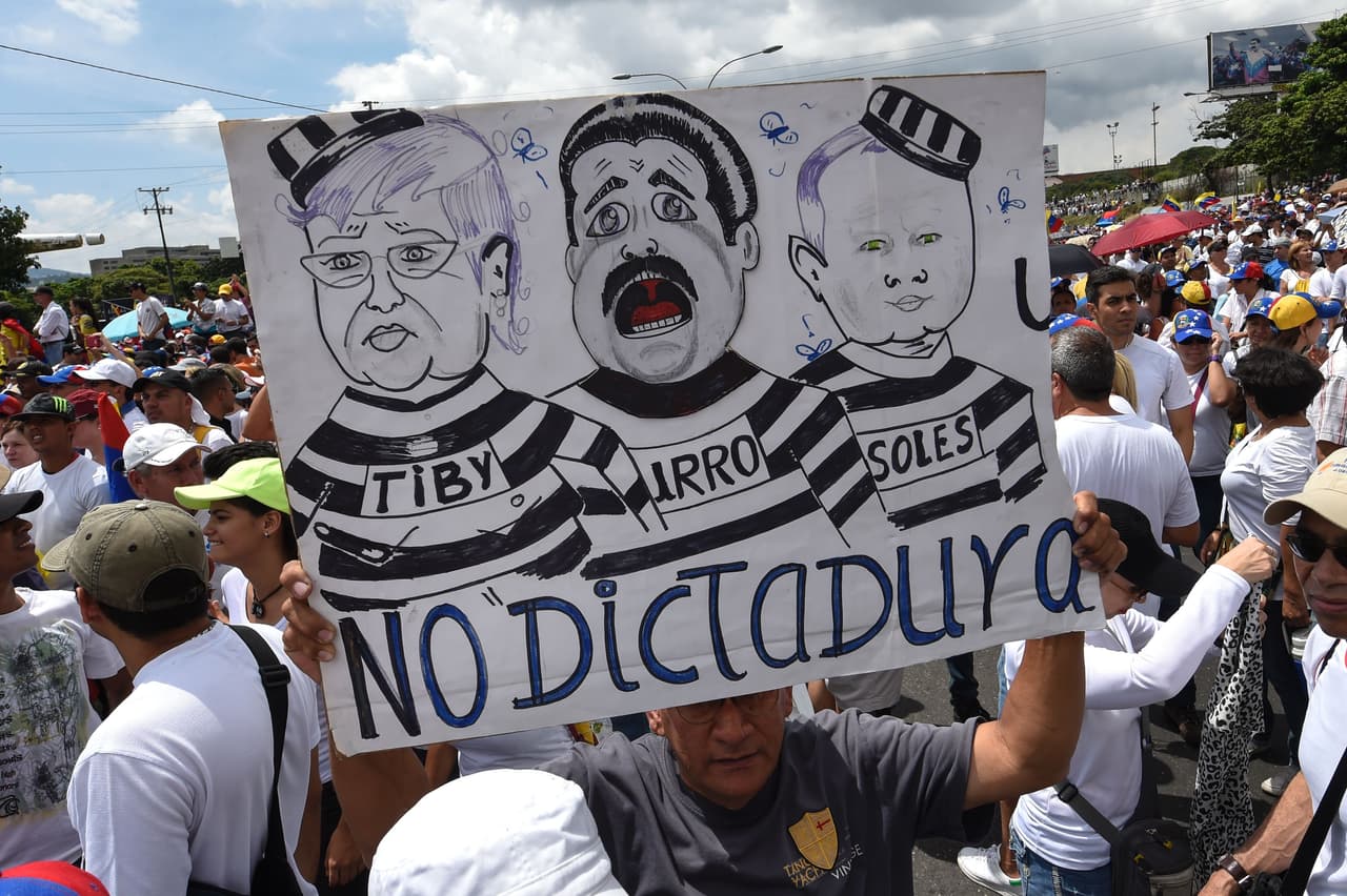 Algunos manifestantes portan carteles que critican a los líderes del gobierno, como este que se mofa de Tibisay Lucena, presidenta del Consejo Nacional Electoral, el presidente Nicolás Maduro y Diosdado Cabello, diputado del chavismo.
