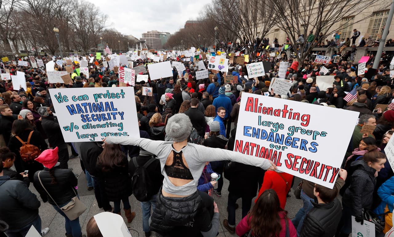 Una mujer posa en Washington con un cartel que dice: "alienar a grandes grupos pone en peligro nuestra seguridad nacional".