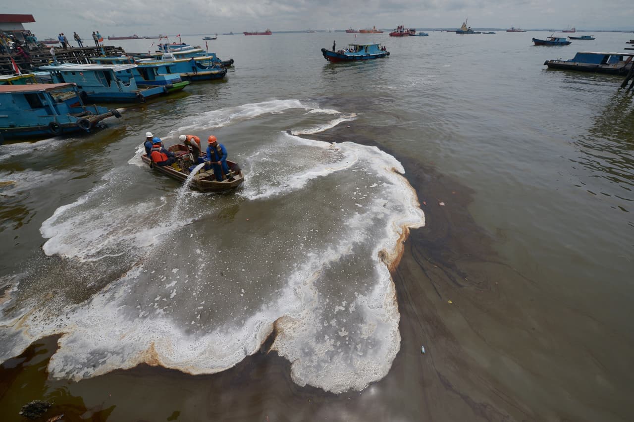 Trabajadores indonesios tratan de limpiar un derrame de petróleo del mar en Balikpapan. El derrame, ocurrido en marzo de 2018 en la isla de Borneo, causó cinco muertes y las autoridades declararon estado de emergencia.